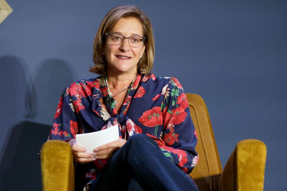 A woman wearing a floral shirt sitting in a chair.