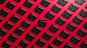 repeating pattern of film slates against a red background; a slate in the middle is open